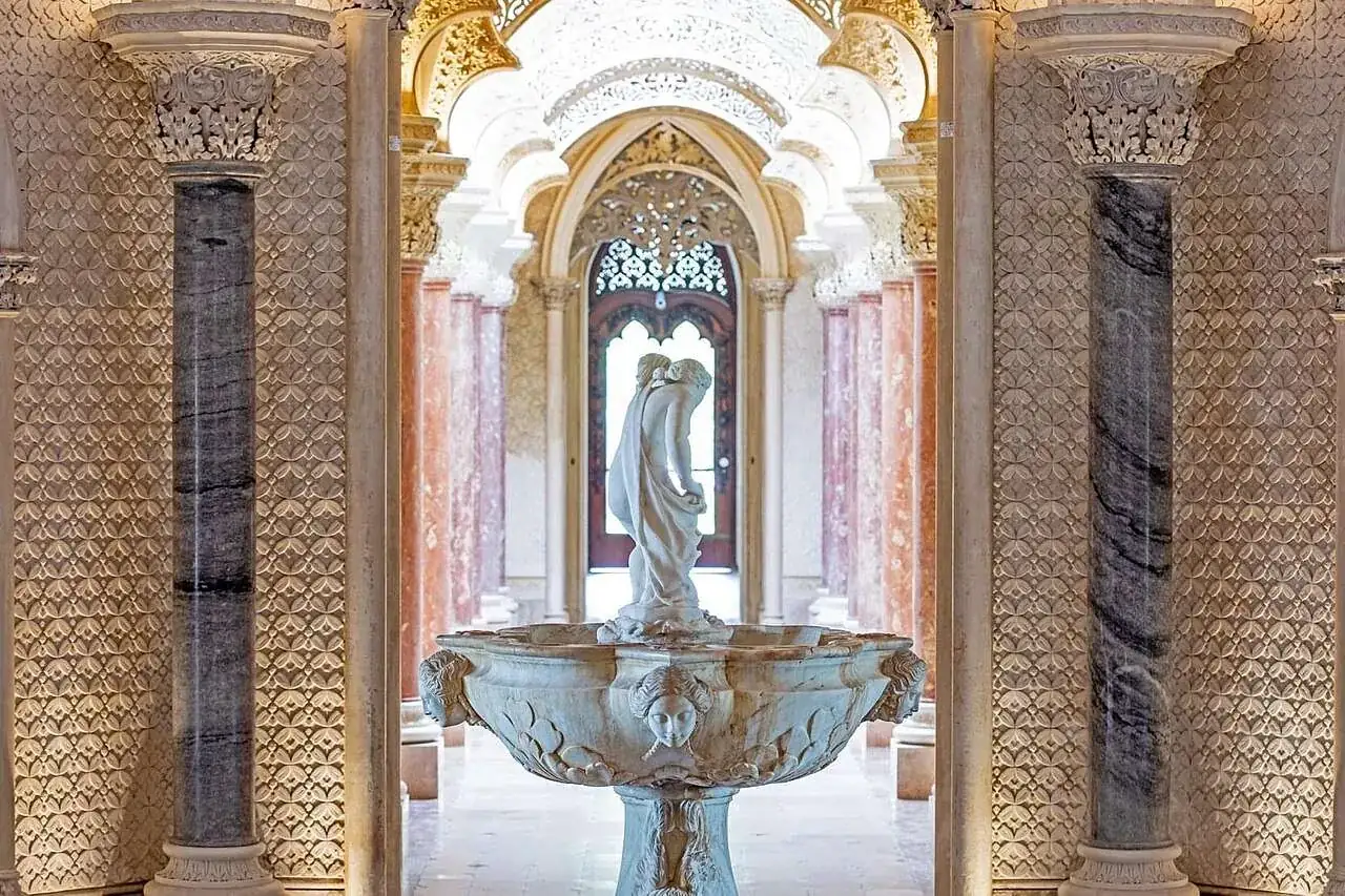 Le hall central : une fontaine en marbre avec une figure debout, encadrée par deux colonnes polies sous un plâtre sculpté et ajouré